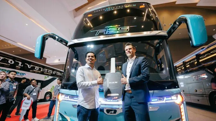 Representatives from MAN and local partners celebrate with a giant decorative key in front of a turquoise New Armada double-decker bus at the Busworld Southeast Asia 2026. (Photo: MAN Truck & Bus)