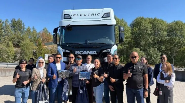 The Ekspres Perdana management delegation posing together with Scania representatives in front of a white Scania electric truck during their visit to Södertälje. (Photo: Ekspres Perdana/Facebook)