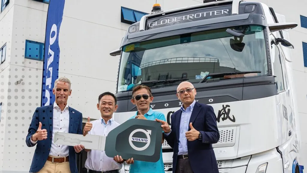 Representatives holding a large ceremonial key in front of a white Volvo FH Globetrotter truck. (Photo: Volvo Trucks Singapore)
