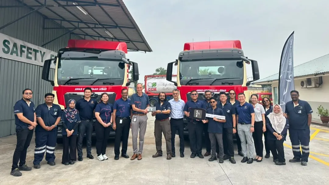 Executives from MAN Malaysia and North-South Transport posing with a ceremonial key in front of two red MAN TGS trucks. (Photo: MAN Malaysia)