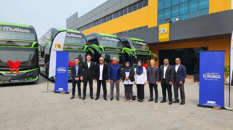 Official handover group photo featuring executives standing in front of four green and black E-Mutiara MAN double-deck coaches decorated with red ribbons.