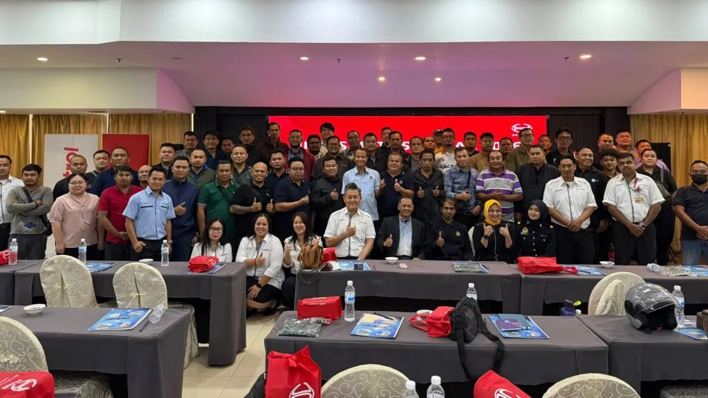 A large group of seminar participants and presenters giving thumbs-up gestures while seated and standing inside a conference hall at Penview Hotel in Kuching.