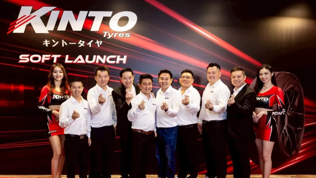 Kinto Tyres executives and brand ambassadors making heart hand gestures in front of a red and black Kinto Tyres Soft Launch backdrop.